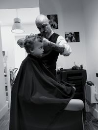 Barber cutting hair of boy at salon