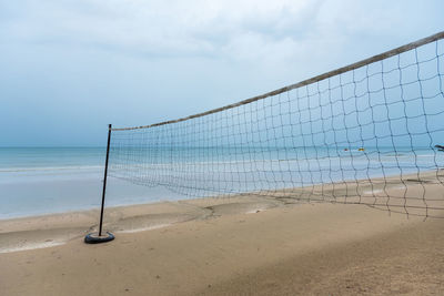 Volleyball net at sea shore against sky