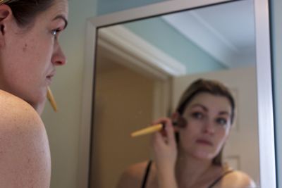 Woman applying make-up at home