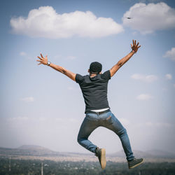 Full length of man jumping against sky