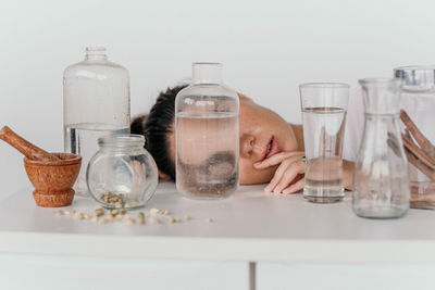 Portrait of a young girl with transparent vessels on a white table