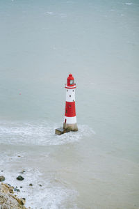 Lighthouse on beach by sea against building