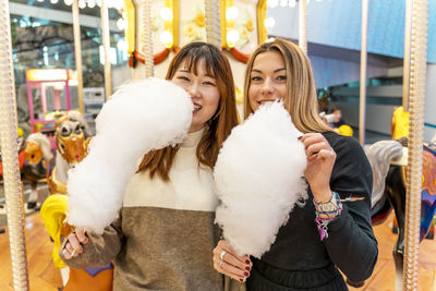 Couple of young multi-ethnic women eating cotton candy at a party. concept of millennial generation