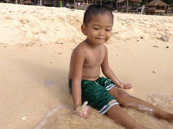 Portrait of happy boy playing on sand at beach