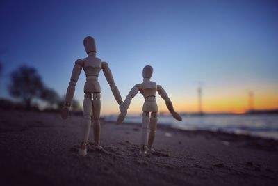 Wooden figurines at beach at sunset