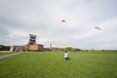 Rear view of man kitesurfing at grassy field