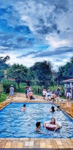 People at swimming pool against sky