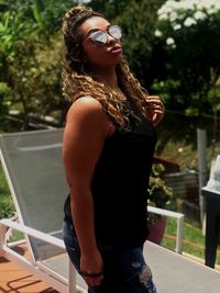 Young woman wearing sunglasses while standing on porch