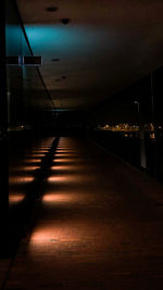 Empty road along illuminated buildings at night