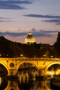 Arch bridge over river against sky at dusk