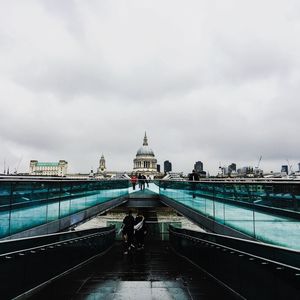 Rear view of woman on bridge against cloudy sky