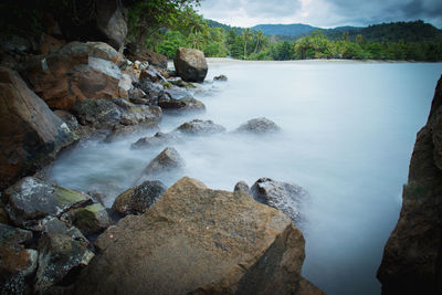 Rocks in sea against mountains