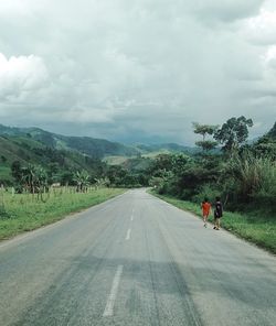 Two local boy walking talking on empty road near mount 