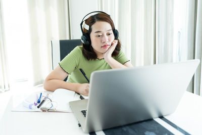 Young woman using phone while sitting on table