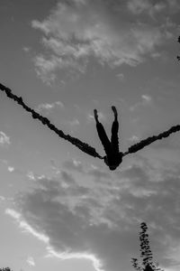 Low angle view of silhouette birds perching on metal against sky