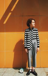 Young woman looking away against wall