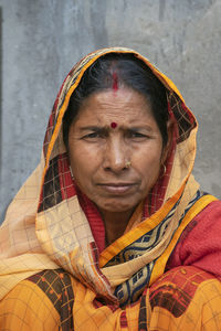 Close-up portrait of woman wearing sari against wall