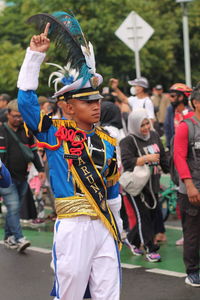 A man leads a marching band, wearing uniform