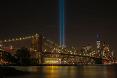 Illuminated bridge over river against sky at night