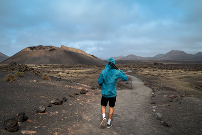 Rear view of man walking on land against sky