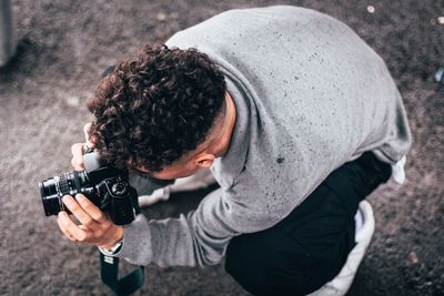High angle view of man photographing while crouching on road