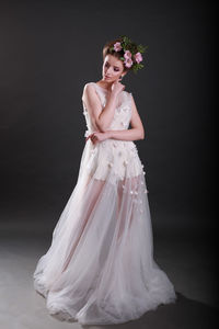 Young woman in wedding dress standing against black background