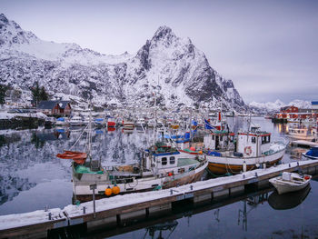 Moored boats in lake against snowed mountains