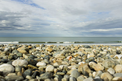 Surface level of pebbles on beach against sky