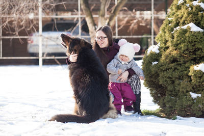 Mother and daughter with dog on snow