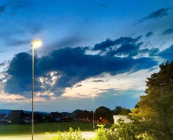 Illuminated street light against cloudy sky