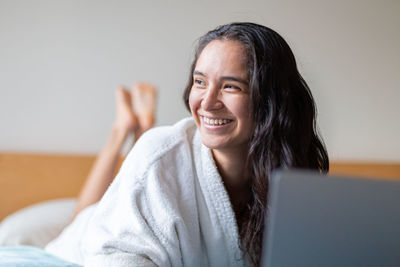 Happy woman surfing internet on laptop in bedroom at home