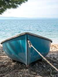 Boat moored on sea shore against sky