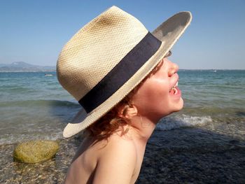 Smiling boy wearing hat against sea