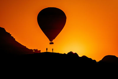 Silhouette of hot air balloon against orange sky