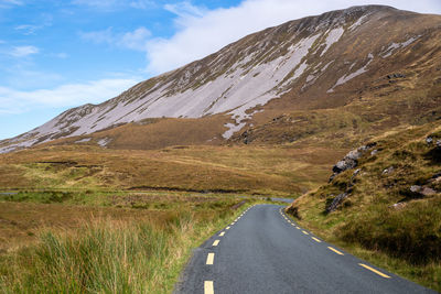 Road leading towards mountains against sky