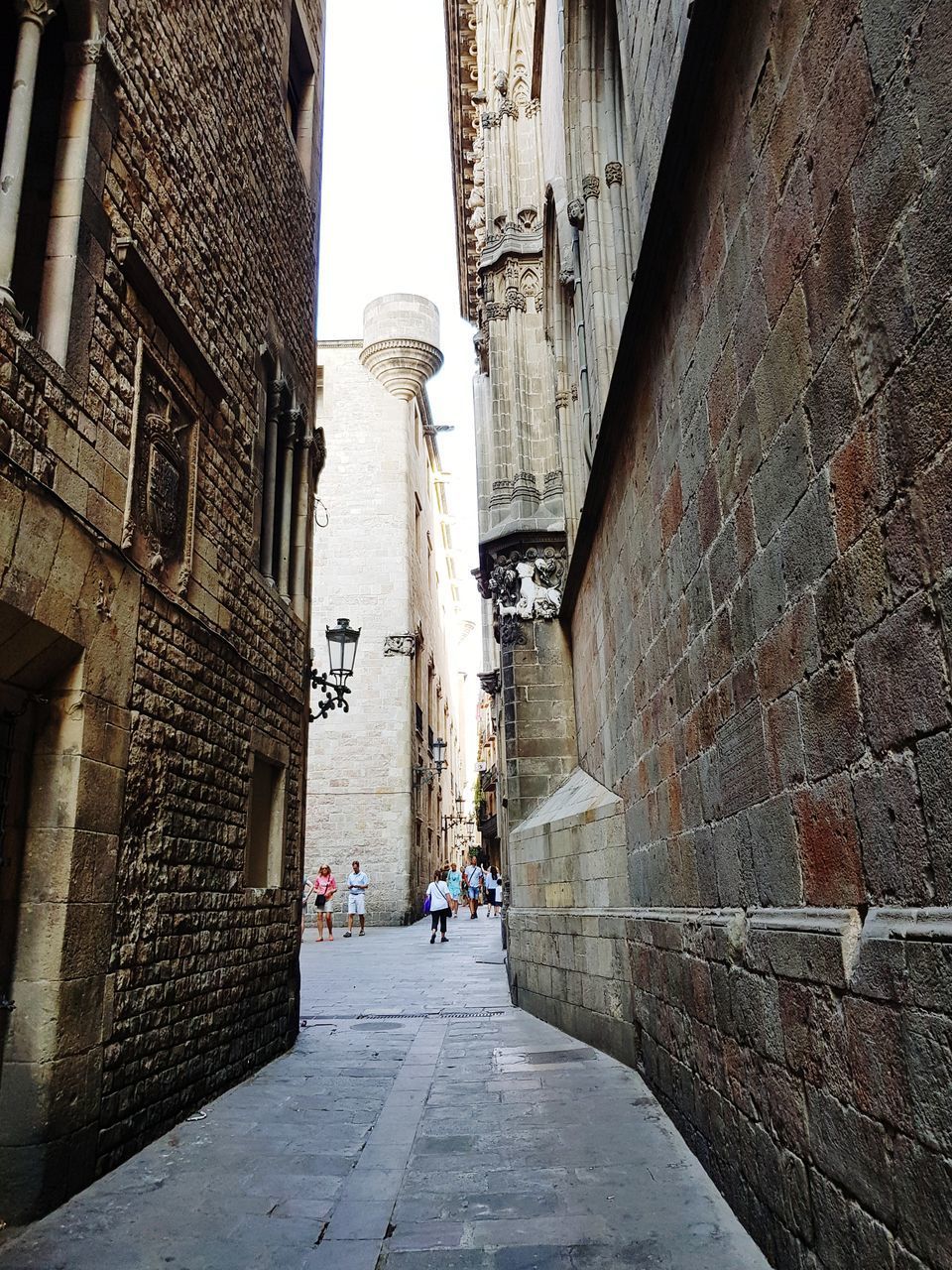 PEOPLE WALKING ON FOOTPATH AGAINST OLD BUILDING