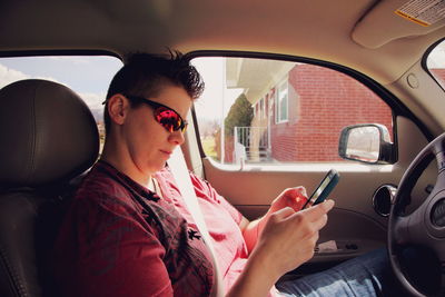 Young woman using mobile phone while sitting in car