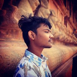 Thoughtful young man by wall looking away