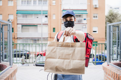 Portrait of delivery person wearing mask giving parcel