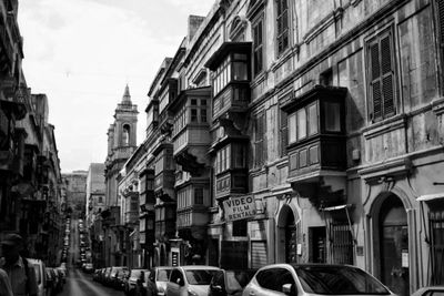 Cars on city street by buildings against sky