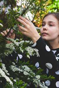 Cute girl holding flowering plant while standing outdoors