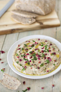 Top view of hummus on wooden table by bread loaf on chopping board