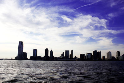 Sea and buildings in city against sky