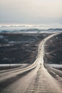 Road passing through prairie landscape towards mountains in winter 