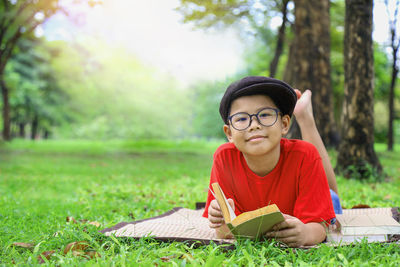 Portrait of boy with book against trees