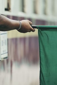 Cropped hand of train dispatcher holding green flag