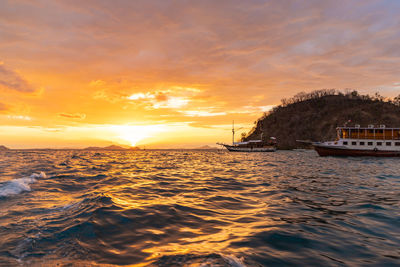 Sailboats sailing in sea against sky during sunset