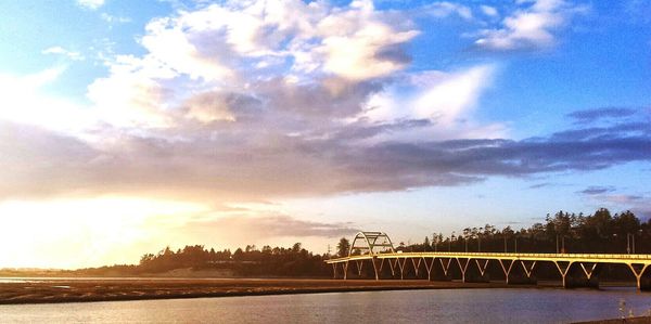 Bridge over river against cloudy sky