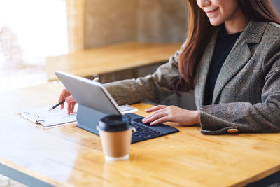 Midsection of businesswoman using digital tablet on table