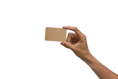 Close-up of hand holding paper against white background